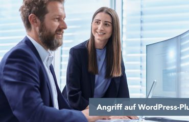 Zwei Kollegen im Büro schauen auf einen Monitor; Text im Bild: Angriff auf WordPress-Plug-ins.