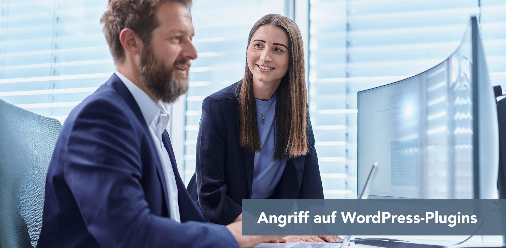 Zwei Kollegen im Büro schauen auf einen Monitor; Text im Bild: Angriff auf WordPress-Plug-ins.