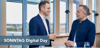 Two men in navy suits chat in a bright, modern space; a blue banner across the bottom reads 'SONNTAG Digital Day'