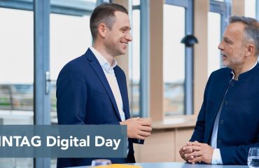 sonntag-header-events Two men in navy suits chat in a bright, modern space; a blue banner across the bottom reads 'SONNTAG Digital Day'